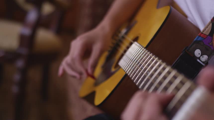 A person strumming on an acoustic guitar using a guitar pick
