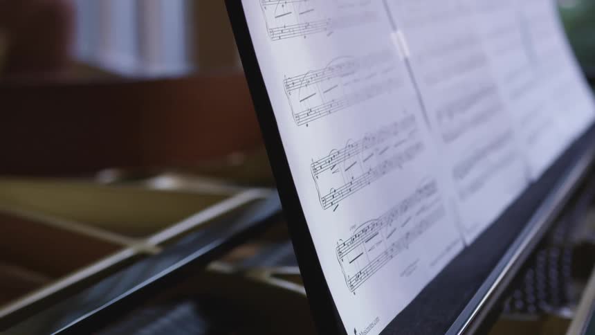 A piano with paper with sheet music above it