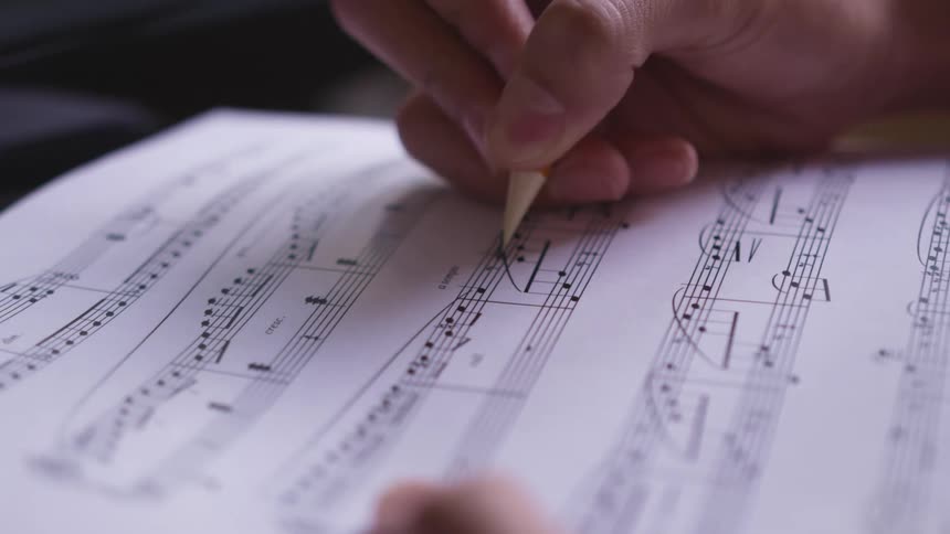 A composer writes music on a music sheet
