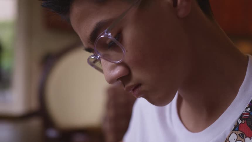 A boy at home looking down and concentrating