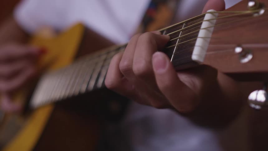 Man with a white shirt plays a guitar by pulling the strings with his fingers