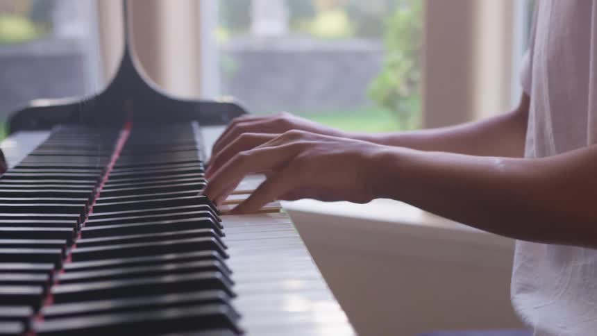 A person plays a piano next to a window