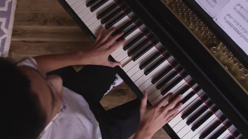 A young man plays a keyboard at home
