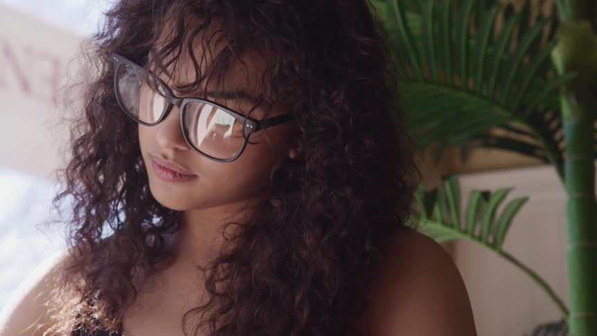 A woman is wearing glasses and sitting indoors