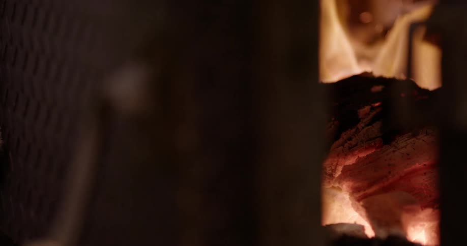 Chunks of wood burn in a furnace as a door closes