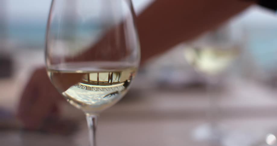 A person places silverware on a table with filled wine glasses