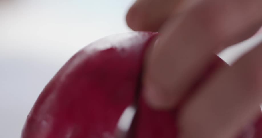 A person slices open a red pomegranate with a sharp knife