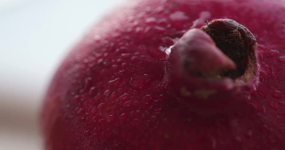 Close up of the red skin of a pomegranate covered in drops of water