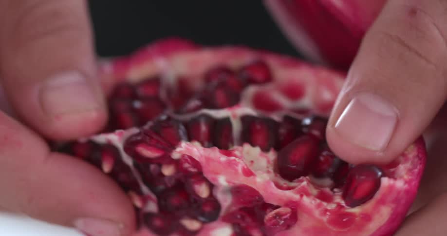 A person peeling a persimmon and removing the seeds