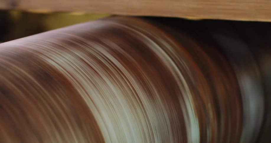 A wood board slides over rotating machinery