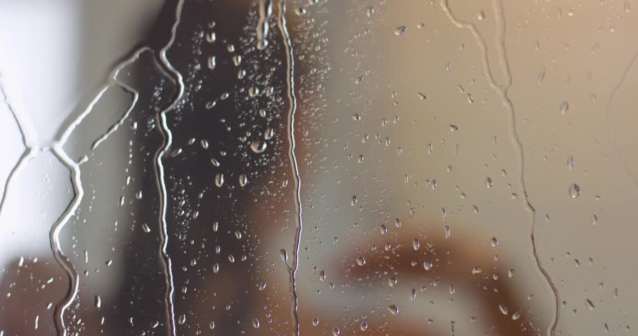 A woman in a shower runs her hands through her hair before exiting the shower
