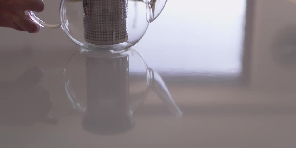 A man sets a teapot down on a table