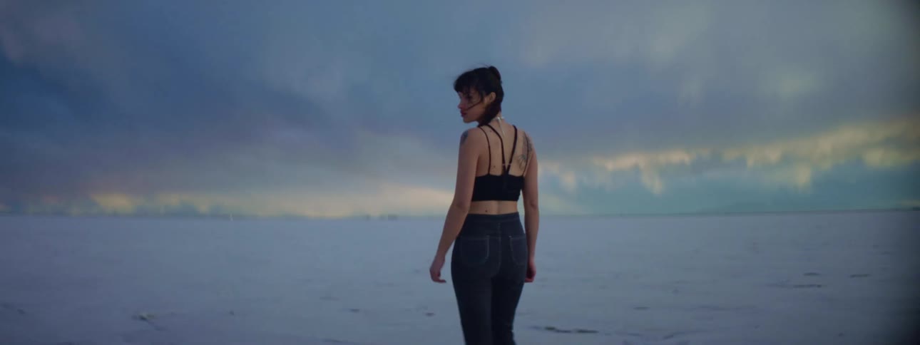 A woman is walking on the beach at dusk