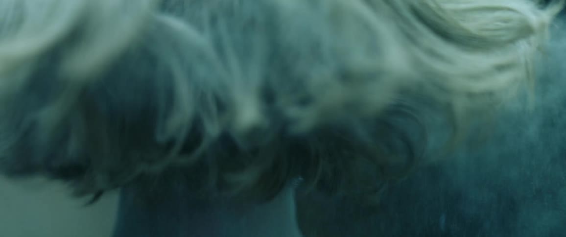 A teenage girl shakes her head as powder flies off of it