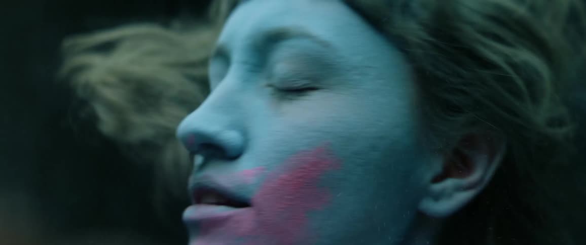 A teenager with zombie like makeup all over her face shakes her head around