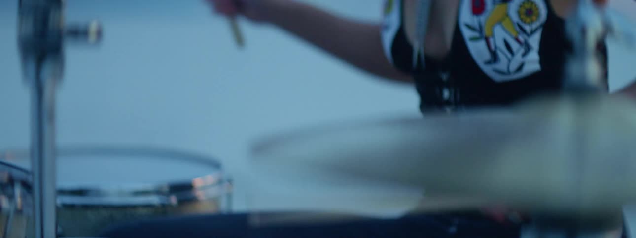 A woman plays the drums at high speed with a pair of wooden drum sticks
