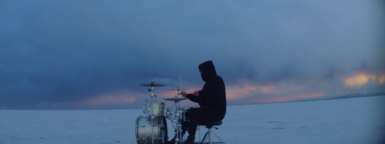 A man playing the drums outside on a snow covered field