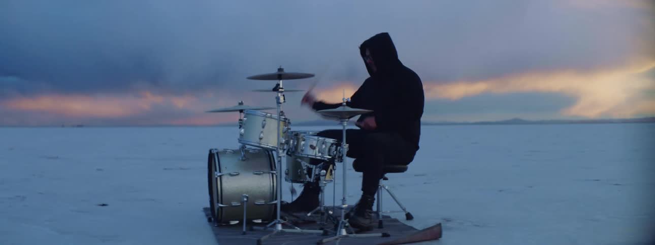 A man plays the drums on snow covered land