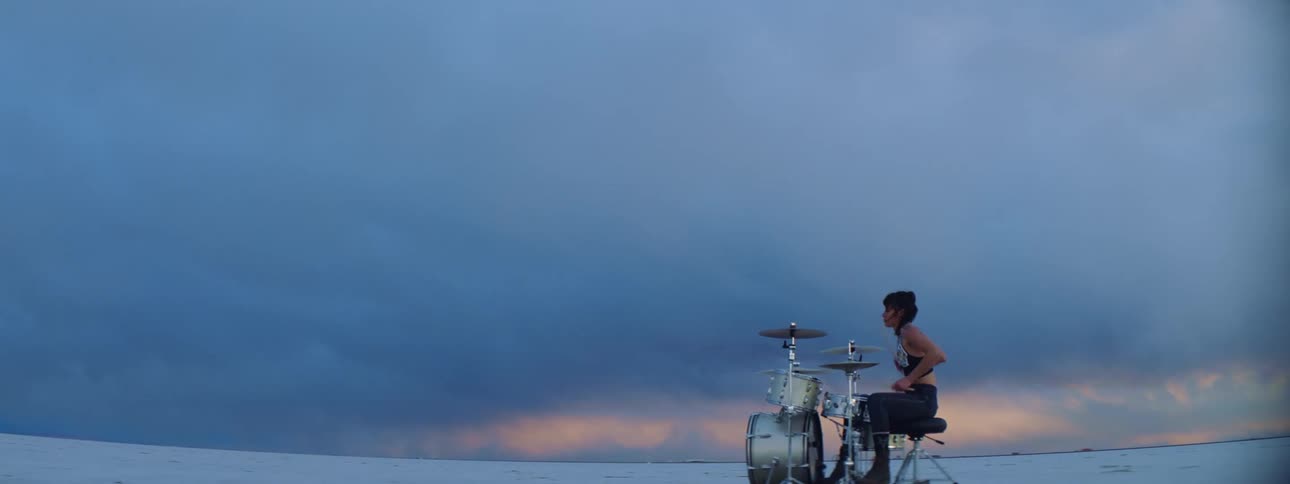 A teenager girl plays the drums out in a snow covered field