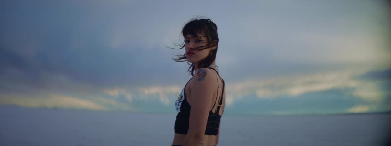A female caucasian standing near a river with the wind blowing in her hair