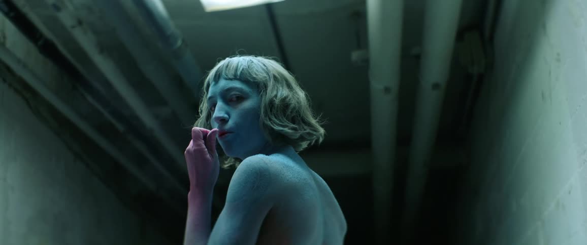 A woman with blue skin is in the dark tunnel