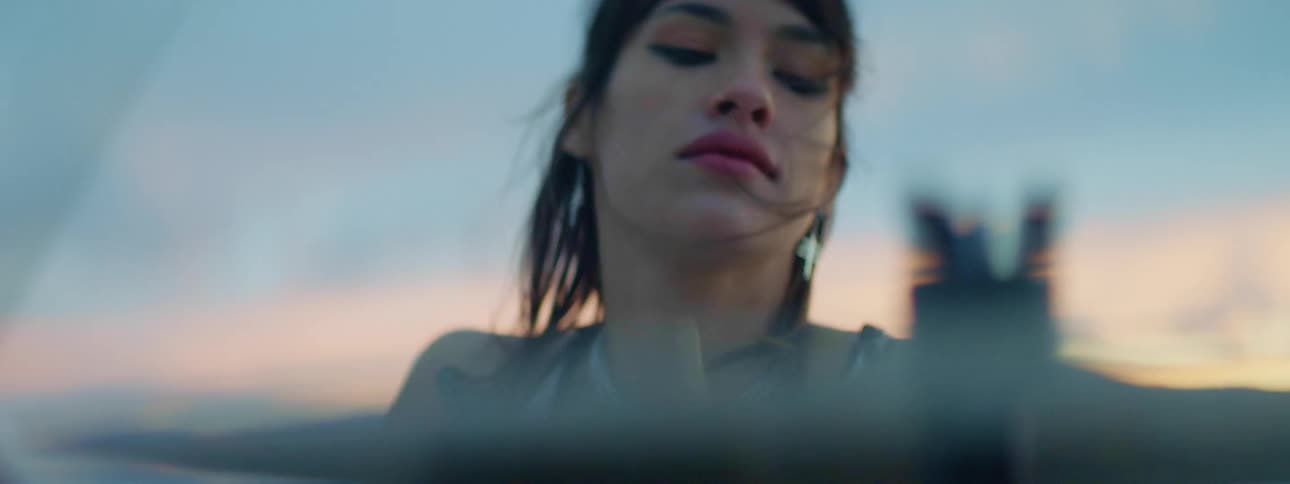 A young woman plays a drum set outdoors in the evening