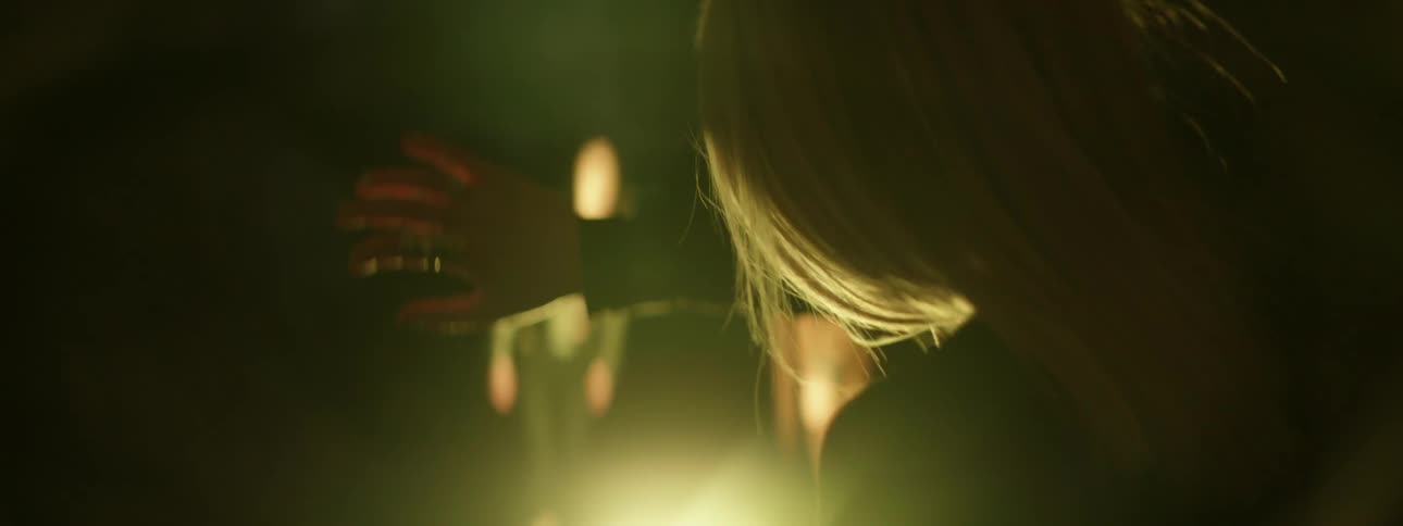 A female holding her hand up surrounded by bright lights