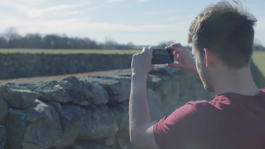 A man takes a photograph outside on a sunny day