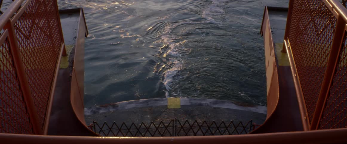 A boat churns up water behind it at sunset