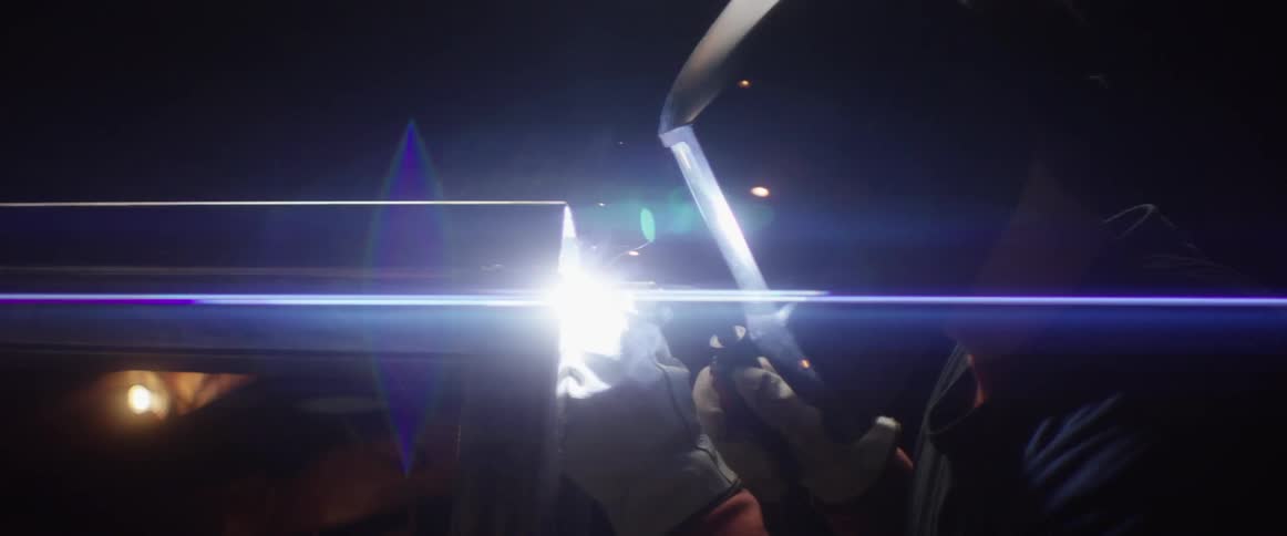 A welder works on a piece of metal with sparks flying around