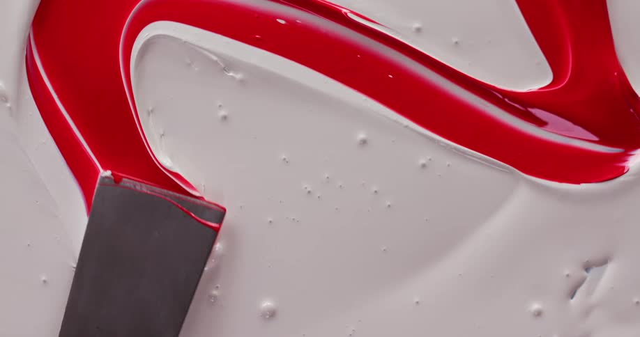 A person traces a swirl of red paint in the white