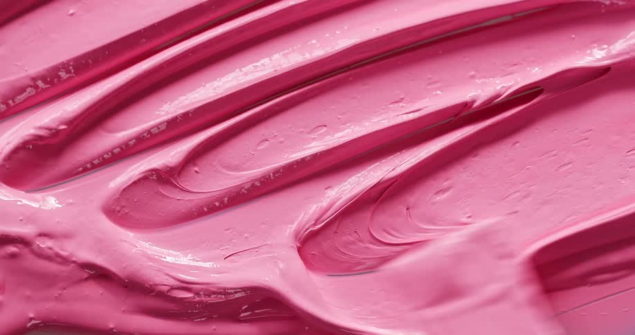 A person spreads pink paint on a surface using a painting knife