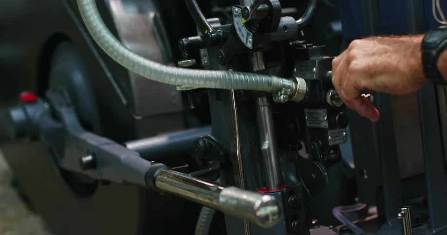 A persons hand with a wrist watch operating a factory machine