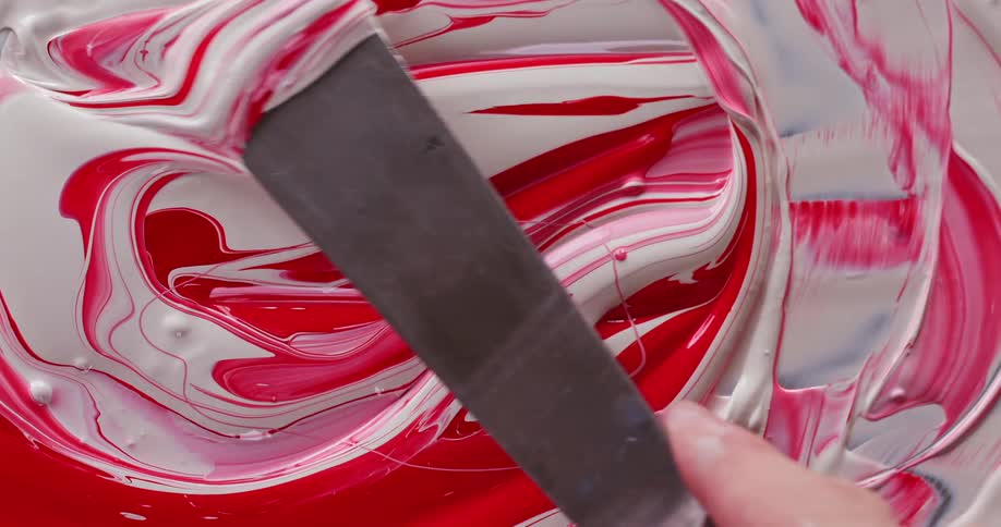 Painter mixes red and white paints with palette knife