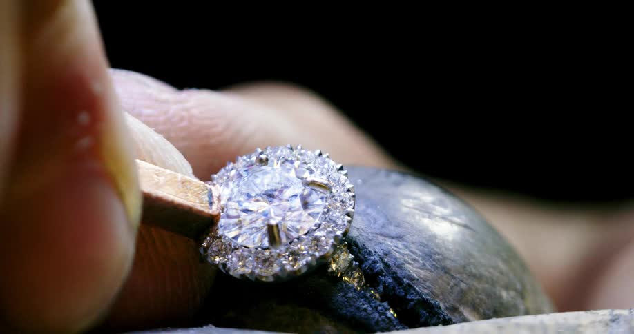 A jeweler secures a prong on a diamond ring