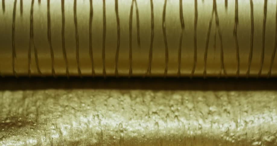Gold liquid beneath a rotating gold roller