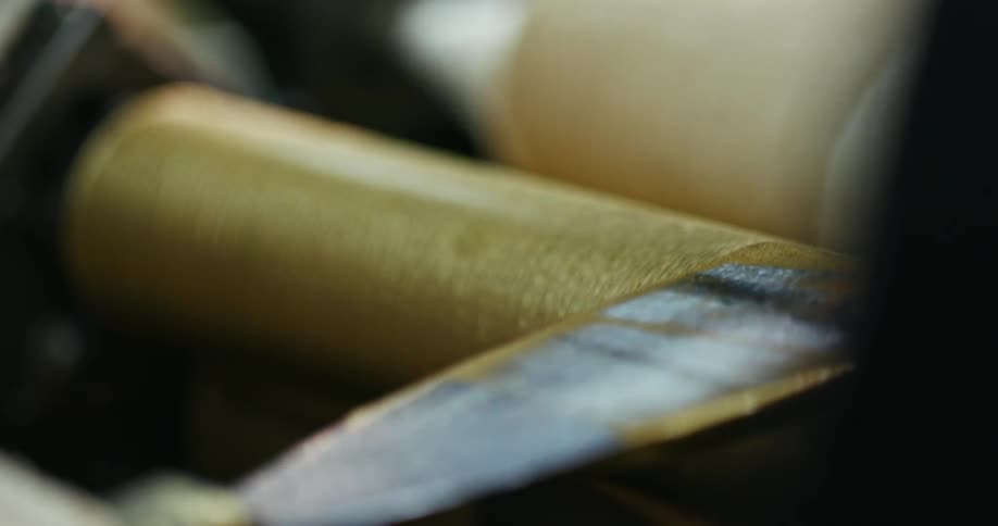 A person with gloves putting gold paint on a roller