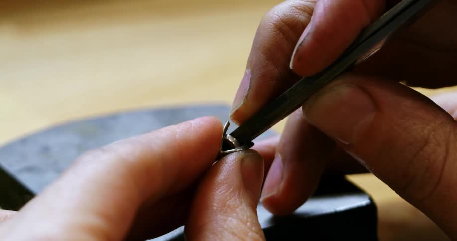 A man uses tweezers to squeeze a clasp together