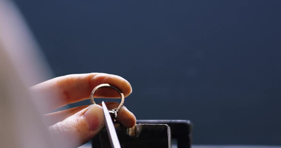 A jeweler uses a file to file down the prongs of a ring without a gem