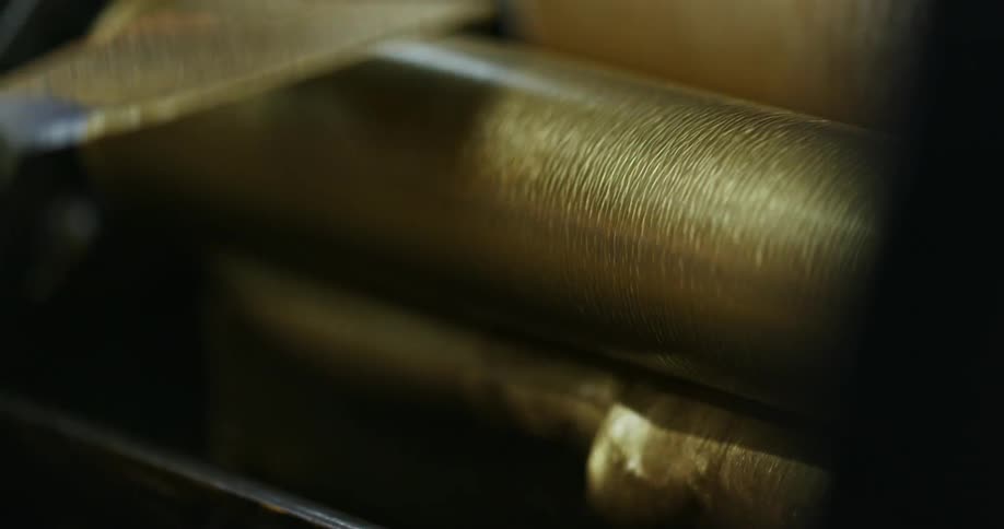 A person with gloves applying gold paint to a roller
