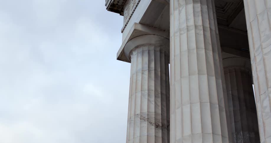 Jet flies over a large building with pillars