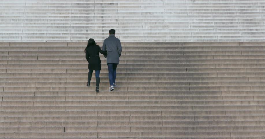 A couple climbs the stairs of a building