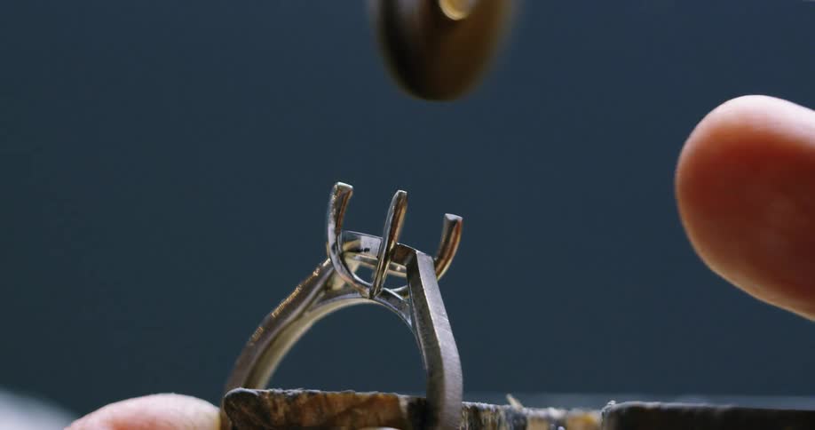 Close up of a bench jeweler polishing the shoulders of a ring