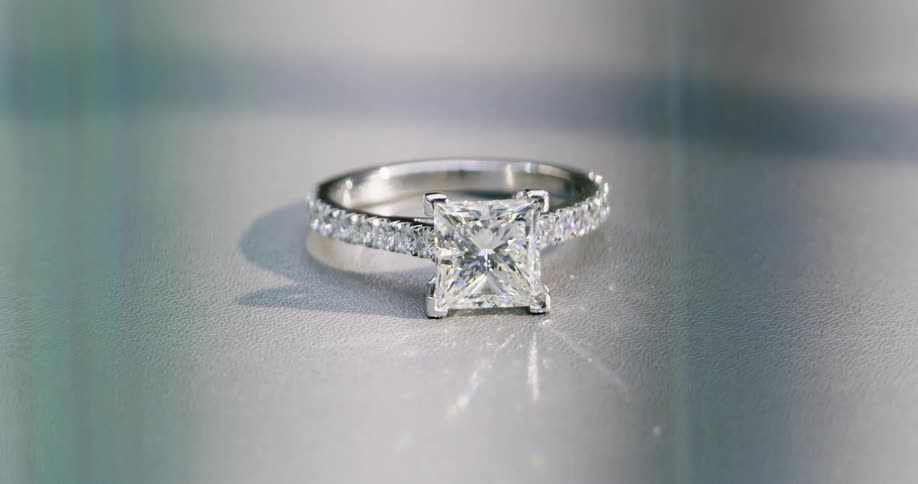 A diamond ring sitting on flat surface glistens in light