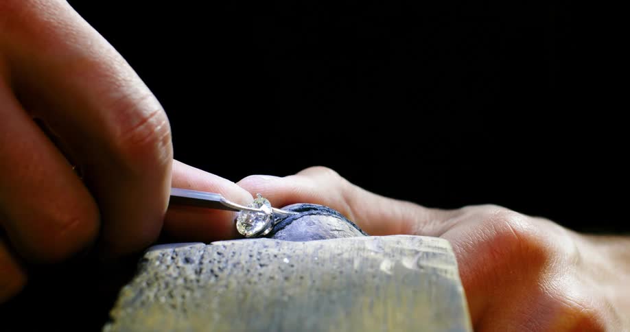Close up of a jeweler extracting the gemstone from a ring using tools