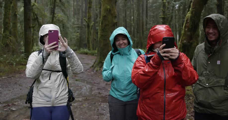 Friends taking pictures in the rain while hiking in the wilderness