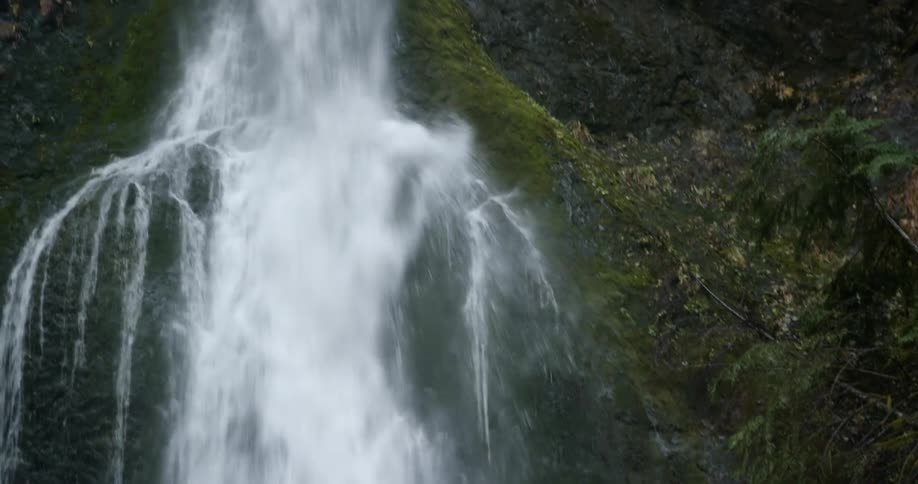 Waterfall flowing over a rock wall covered in green moss and algae