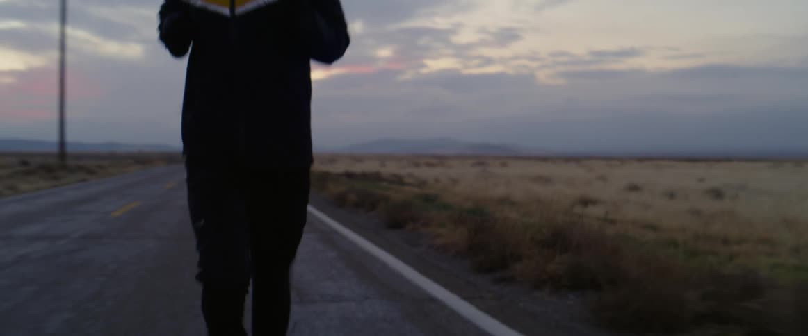 A man running along a road next to a field