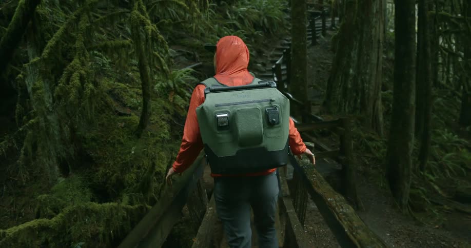A man hikes across a bridge in a forest