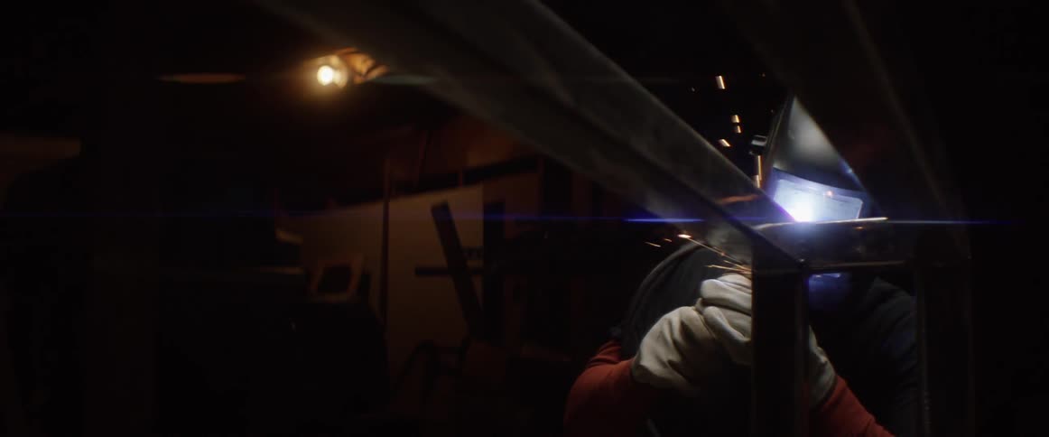 A man is welding some metal in a dark area